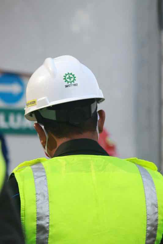 A contractor in a hard hat and high-visibility vest on a job site